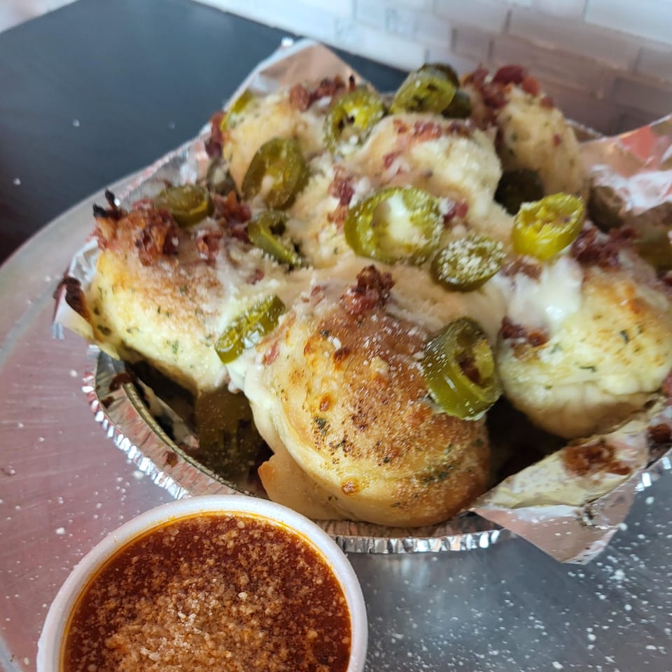 Pana Roma Pizza & Pasta's cheesy garlic knots with jalapeños and bacon, served with marinara sauce.