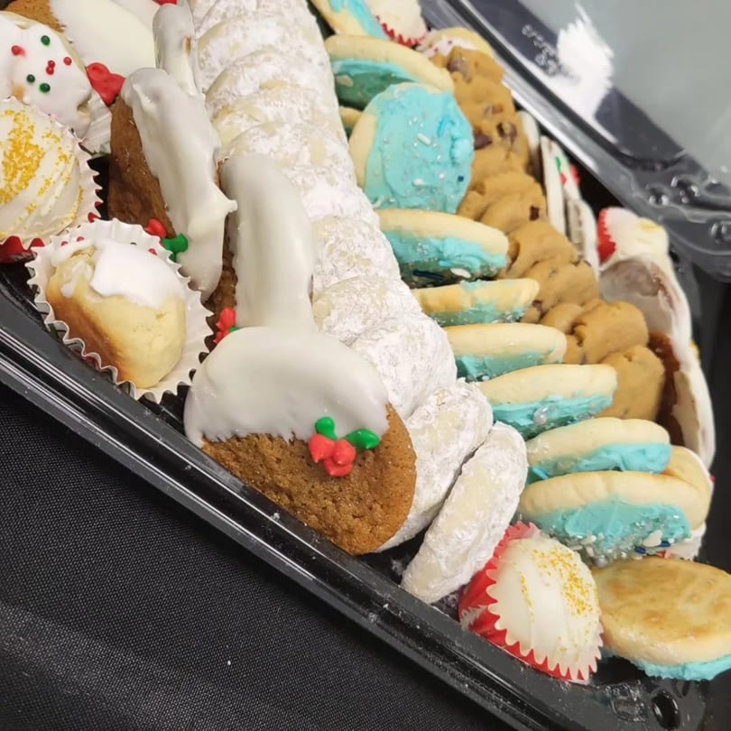 A catering tray filled with various Italian cookies, including powdered sugar, iced, and sprinkle-decorated.