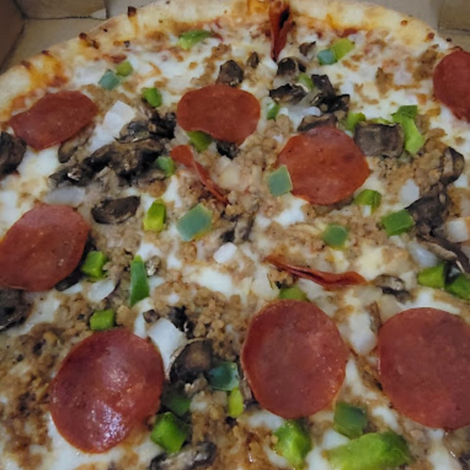 Close-up of a Pana Roma Pizza with pepperoni, sausage, mushrooms, onions, and green peppers.